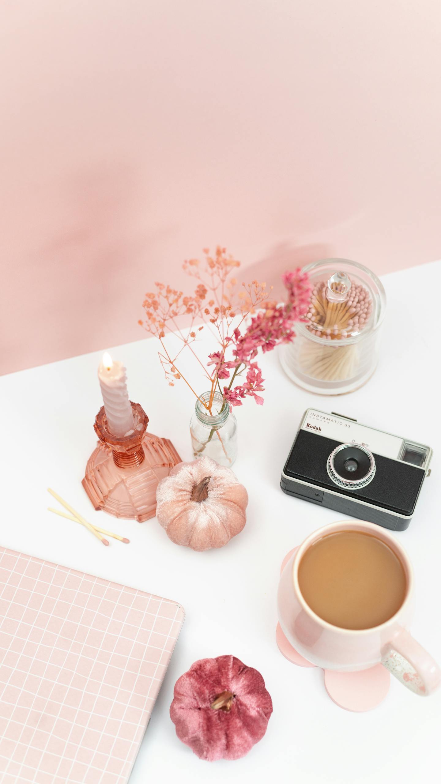 Flat lay design of a pink-themed desk with coffee, camera, and decorative items.