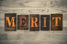 The word MERIT spelled out in bold, rustic, orange letters on individual tiles set against a wooden background.